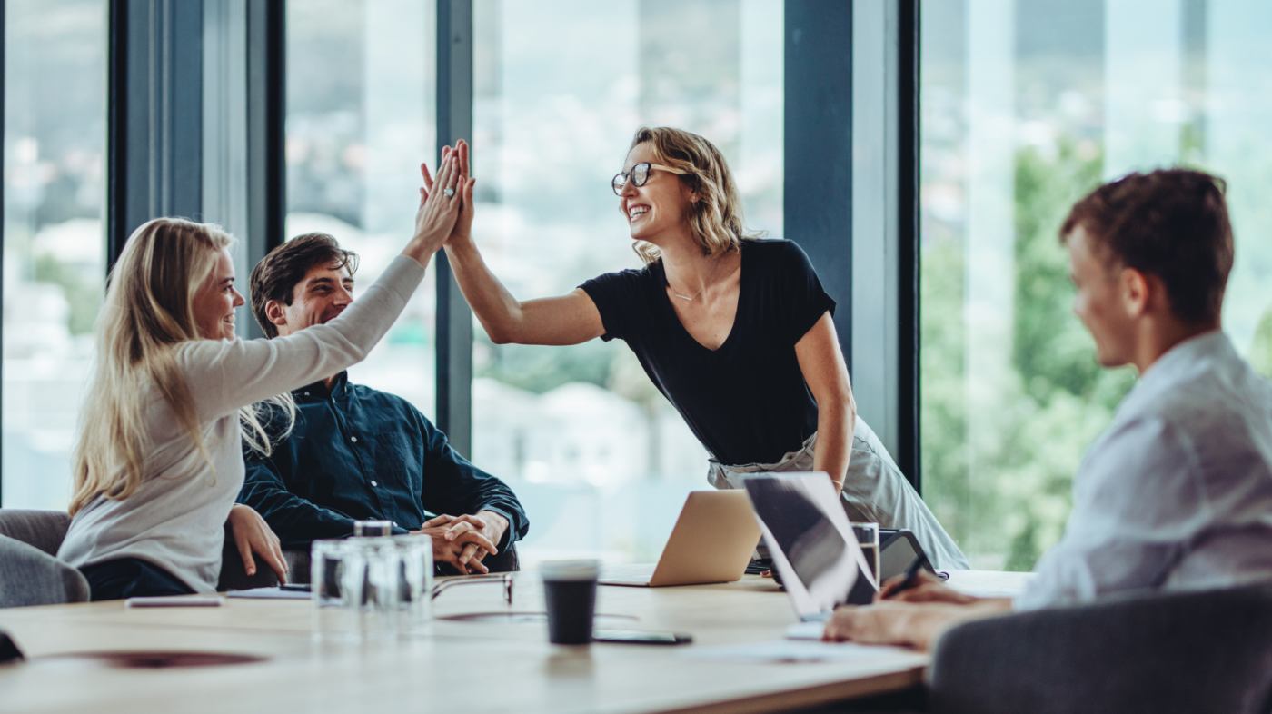 Two women give each other a high five in a meeting.